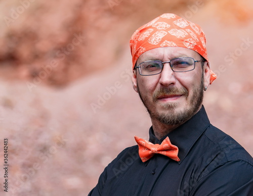 Portrait of a smiling European man in a bandana and bow tie in summer close-up