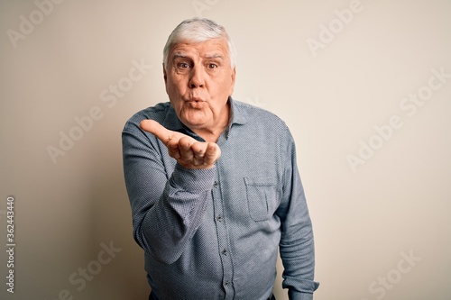 Senior handsome hoary man wearing casual shirt standing over isolated white background looking at the camera blowing a kiss with hand on air being lovely and sexy. Love expression.