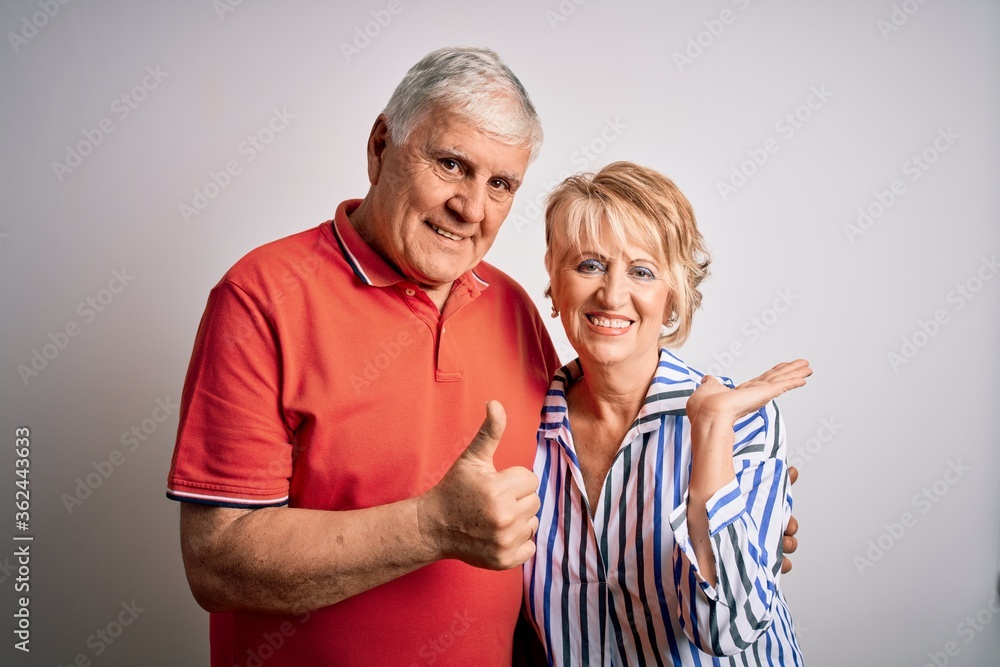 Senior beautiful couple standing together over isolated white background Showing palm hand and doing ok gesture with thumbs up, smiling happy and cheerful Senior beautiful couple standing together over isolated white background Showing palm hand and doing ok gesture with thumbs up, smiling happy and cheerful