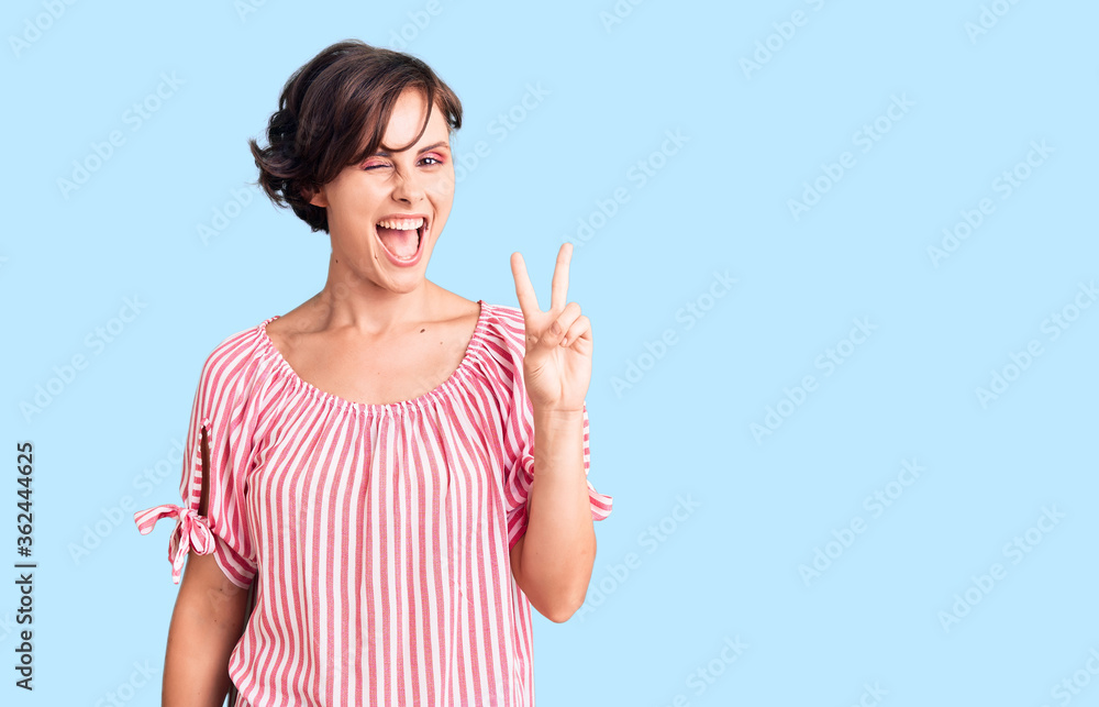 Beautiful young woman with short hair wearing casual summer clothes smiling with happy face winking at the camera doing victory sign with fingers. number two. Beautiful young woman with short hair wearing casual summer clothes smiling with happy face winking at the camera doing victory sign with fingers. number two.