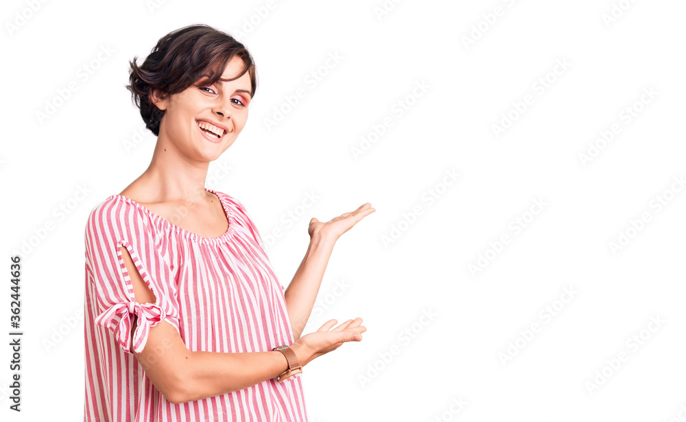 Beautiful young woman with short hair wearing casual summer clothes inviting to enter smiling natural with open hand Beautiful young woman with short hair wearing casual summer clothes inviting to enter smiling natural with open hand