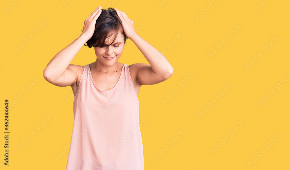 Beautiful young woman with short hair wearing casual style with sleeveless shirt suffering from headache desperate and stressed because pain and migraine. hands on head. Beautiful young woman with short hair wearing casual style with sleeveless shirt suffering from headache desperate and stressed because pain and migraine. hands on head.