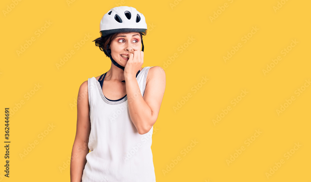 Beautiful young woman with short hair wearing bike helmet looking stressed and nervous with hands on mouth biting nails. anxiety problem. Beautiful young woman with short hair wearing bike helmet looking stressed and nervous with hands on mouth biting nails. anxiety problem.