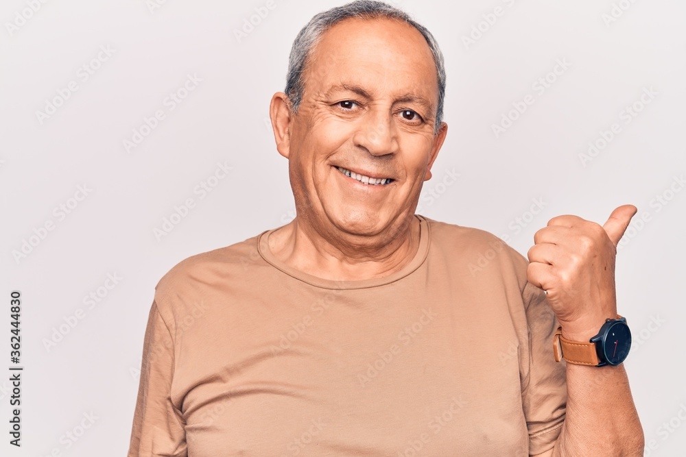Senior man with grey hair wearing casual t-shirt pointing thumb up to the side smiling happy with open mouth Senior man with grey hair wearing casual t-shirt pointing thumb up to the side smiling happy with open mouth
