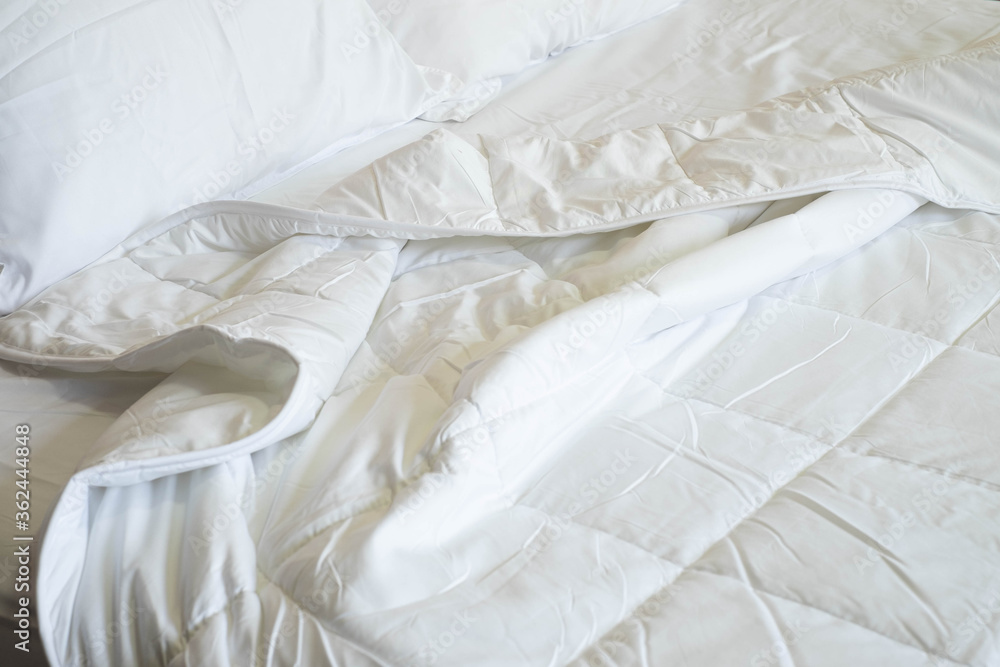Close-up of clean white soft duvet with pillows and bed sheets on the comfortable bed in the bedroom.