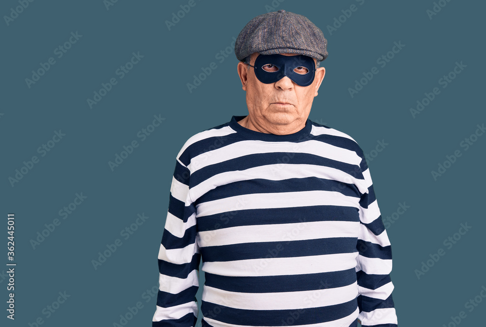Senior handsome man wearing burglar mask and t-shirt skeptic and nervous, frowning upset because of problem. negative person.