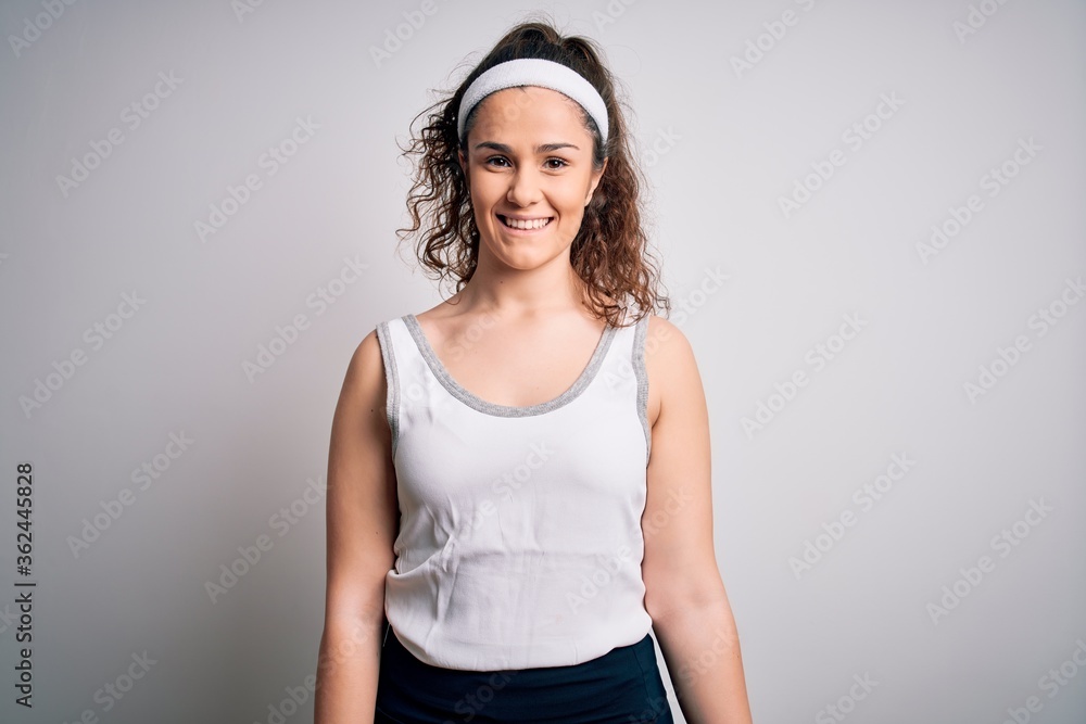 Beautiful sportswoman with curly hair wearing sportswear over isolated white background with a happy and cool smile on face. Lucky person. Beautiful sportswoman with curly hair wearing sportswear over isolated white background with a happy and cool smile on face. Lucky person.