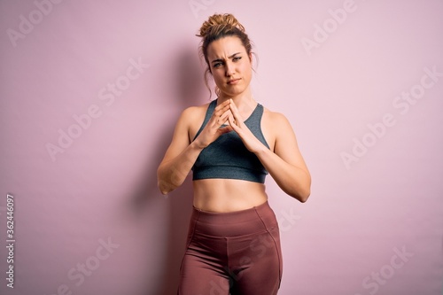 Young beautiful blonde sportswoman doing sport wearing sportswear over pink background Hands together and fingers crossed smiling relaxed and cheerful. Success and optimistic © Krakenimages.com