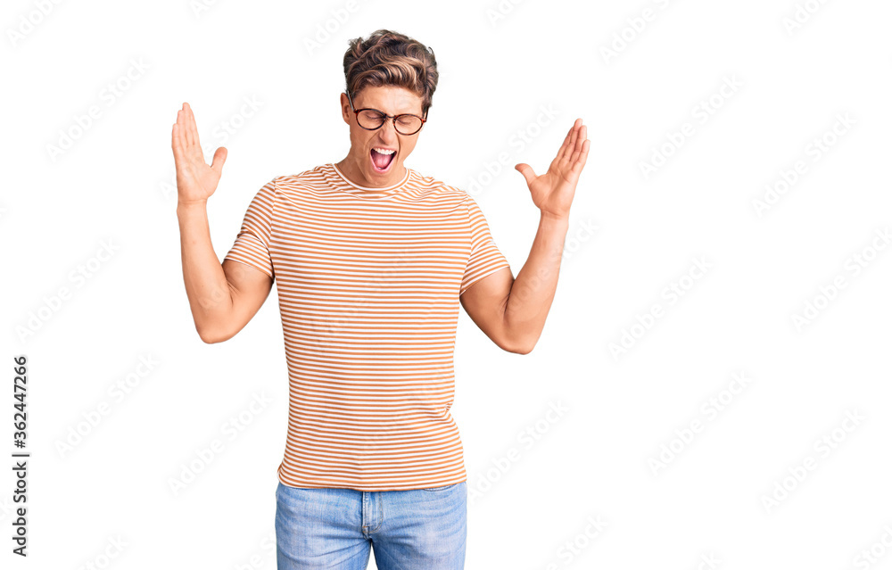 Young handsome man wearing casual clothes and glasses celebrating mad and crazy for success with arms raised and closed eyes screaming excited. winner concept Young handsome man wearing casual clothes and glasses celebrating mad and crazy for success with arms raised and closed eyes screaming excited. winner concept