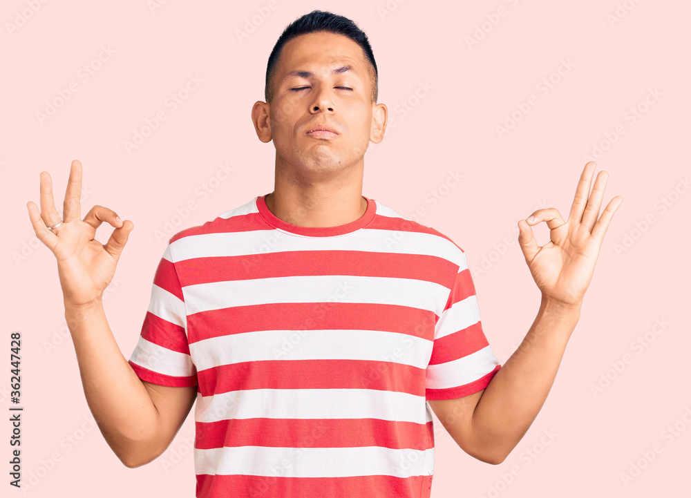Young handsome latin man wearing casual clothes relax and smiling with eyes closed doing meditation gesture with fingers. yoga concept. Young handsome latin man wearing casual clothes relax and smiling with eyes closed doing meditation gesture with fingers. yoga concept.