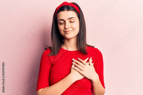Young beautiful girl wearing casual t shirt and diadem smiling with hands on chest, eyes closed with grateful gesture on face. health concept.