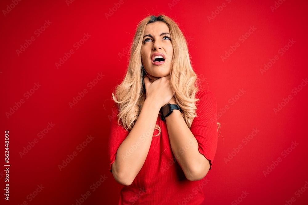 Young beautiful blonde woman wearing casual t-shirt standing over isolated red background shouting suffocate because painful strangle. Health problem. Asphyxiate and suicide concept. Young beautiful blonde woman wearing casual t-shirt standing over isolated red background shouting suffocate because painful strangle. Health problem. Asphyxiate and suicide concept.