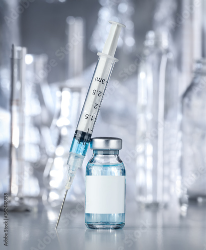 Healthcare and pharmaceutical drugs concept with syringe and vaccine vial with blue liquid. Drug vial has blank white label copyspace.