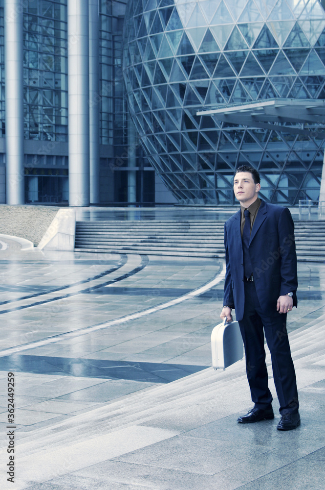 Obraz premium A guy in business suit carrying a briefcase waiting outside the lobby