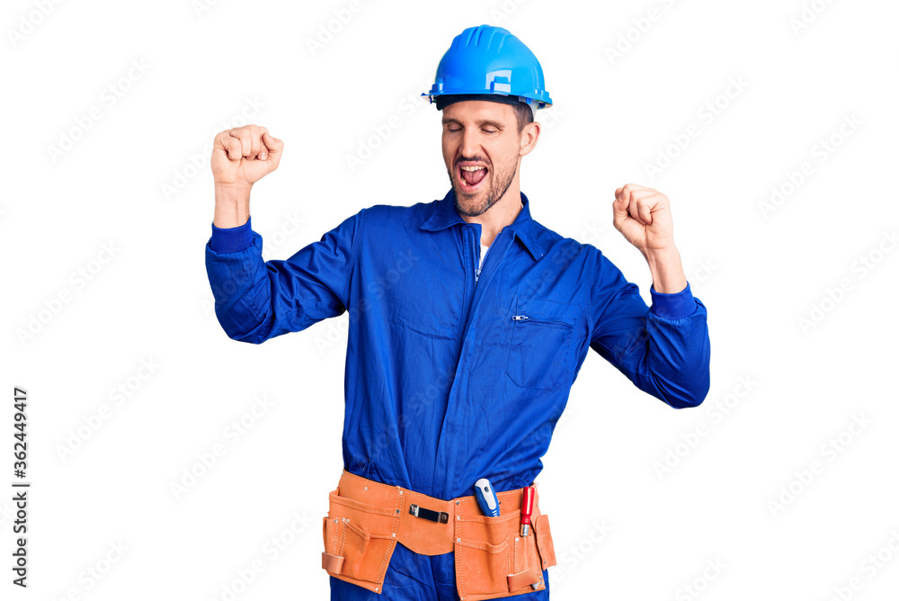 Young handsome man wearing worker uniform and hardhat dancing happy and cheerful, smiling moving casual and confident listening to music