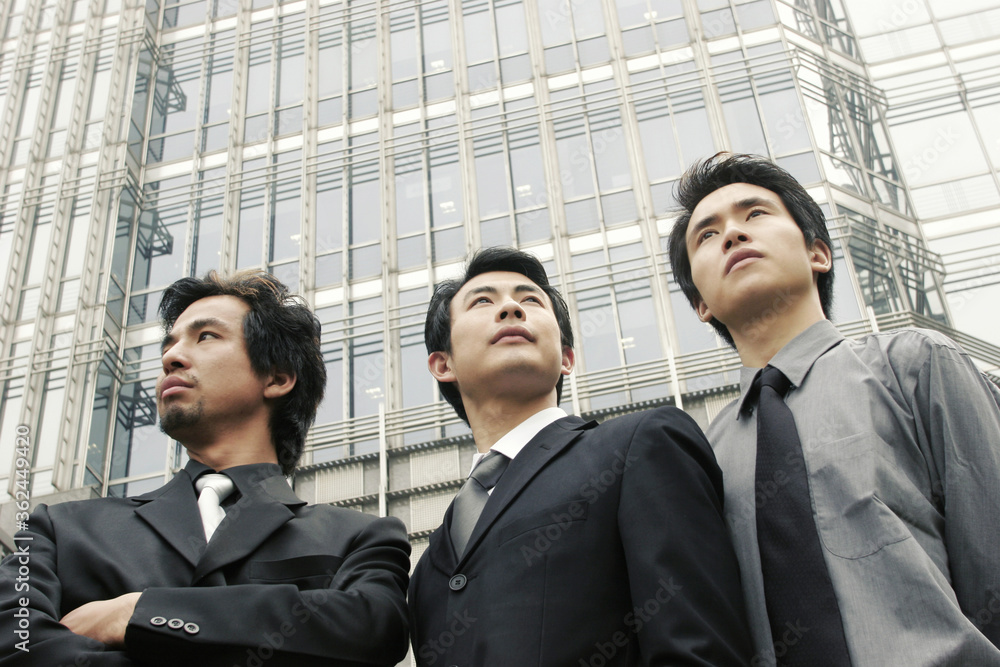Three guys in office attire standing in front of the building Three guys in office attire standing in front of the building
