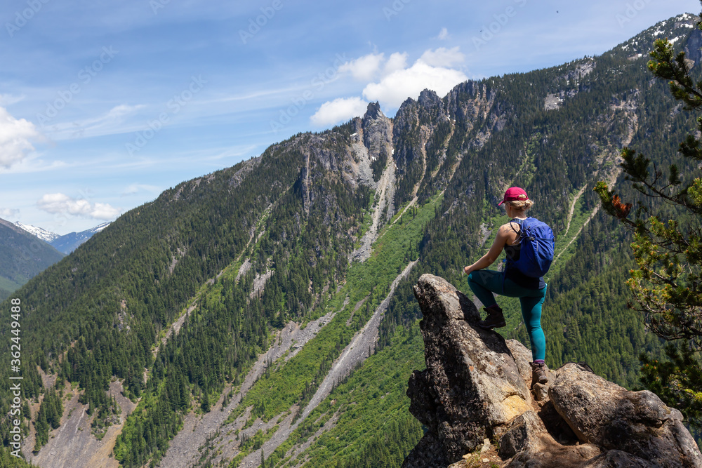 Girl on Top of Cliff with Beautiful View of Canadian Mountain Landscape during a vibrant sunny day. Taken on a Hike to Goat Ridge in Chilliwack, East of Vancouver, British Columbia, Canada.