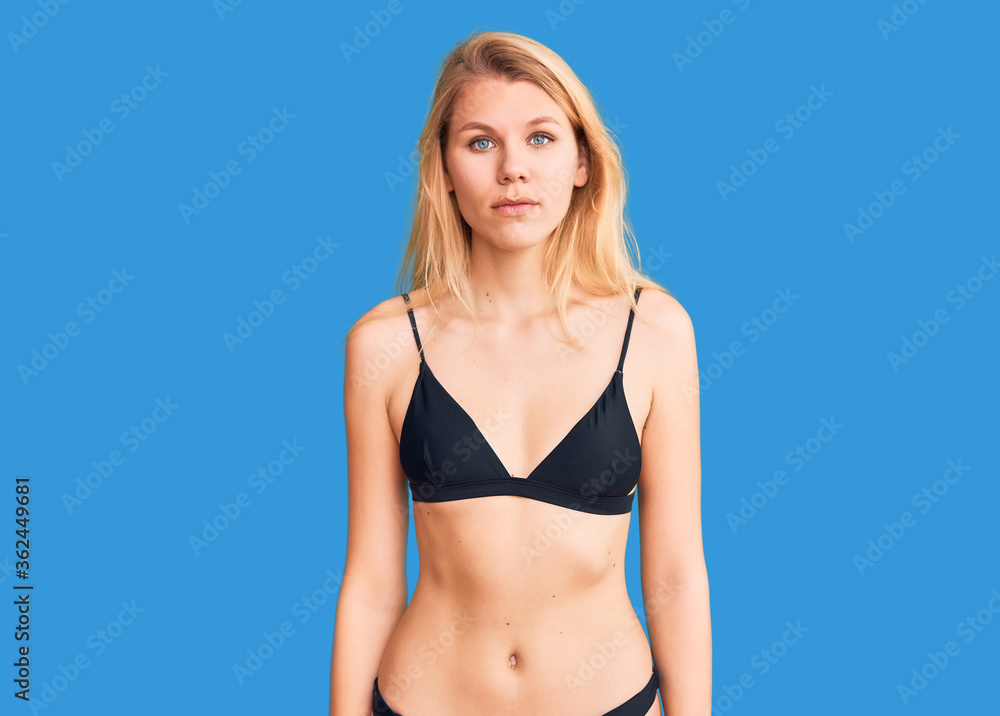 Young beautiful blonde woman wearing bikini relaxed with serious expression on face. simple and natural looking at the camera. Young beautiful blonde woman wearing bikini relaxed with serious expression on face. simple and natural looking at the camera.