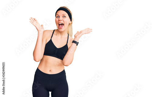 Young beautiful blonde woman wearing sportswear celebrating crazy and amazed for success with arms raised and open eyes screaming excited. winner concept © Krakenimages.com