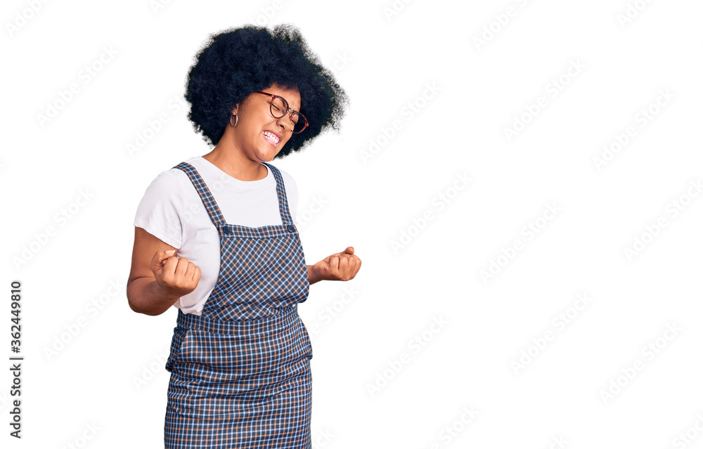 Young african american girl wearing casual clothes very happy and excited doing winner gesture with arms raised, smiling and screaming for success. celebration concept. Young african american girl wearing casual clothes very happy and excited doing winner gesture with arms raised, smiling and screaming for success. celebration concept.