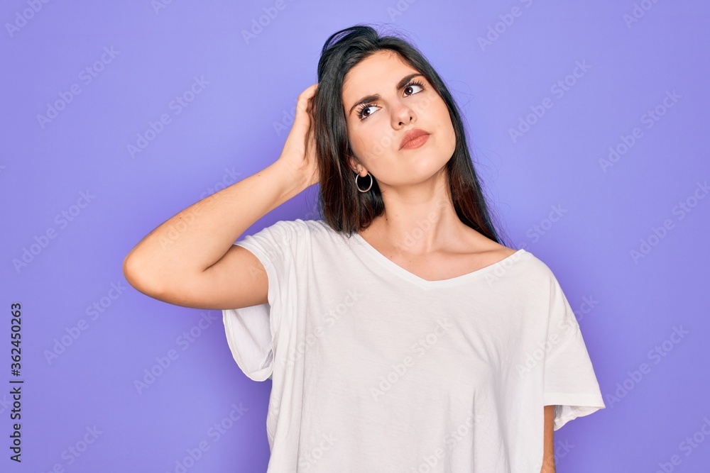 Young beautiful brunette woman wearing casual white t-shirt over purple background confuse and wondering about question. Uncertain with doubt, thinking with hand on head. Pensive concept. Young beautiful brunette woman wearing casual white t-shirt over purple background confuse and wondering about question. Uncertain with doubt, thinking with hand on head. Pensive concept.
