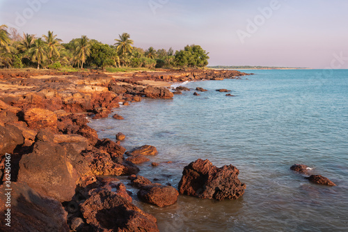 Unspoiled beach at sunset. Rocky landscape, green trees and palm trees. Coastline of Timor sea. Dundee Beach. Northern Territory NT, Australia