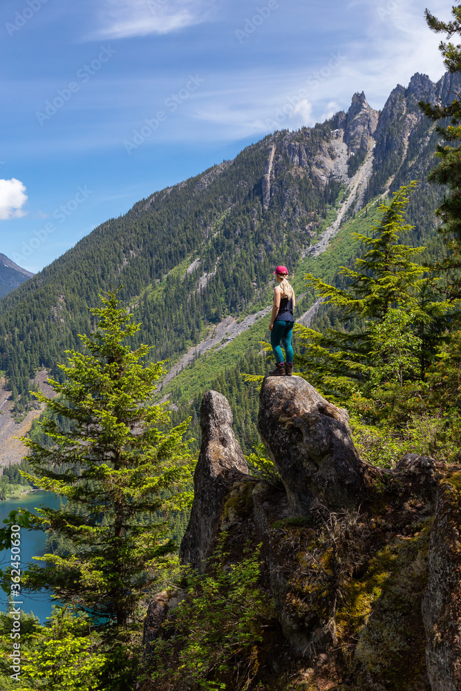 Girl on Top of Cliff with Beautiful View of Canadian Mountain Landscape during a vibrant sunny day. Taken on a Hike to Goat Ridge in Chilliwack, East of Vancouver, British Columbia, Canada. Girl on Top of Cliff with Beautiful View of Canadian Mountain Landscape during a vibrant sunny day. Taken on a Hike to Goat Ridge in Chilliwack, East of Vancouver, British Columbia, Canada.