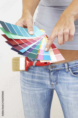 Vászonkép A woman in jeans pointing at the selected colour from the colour cards