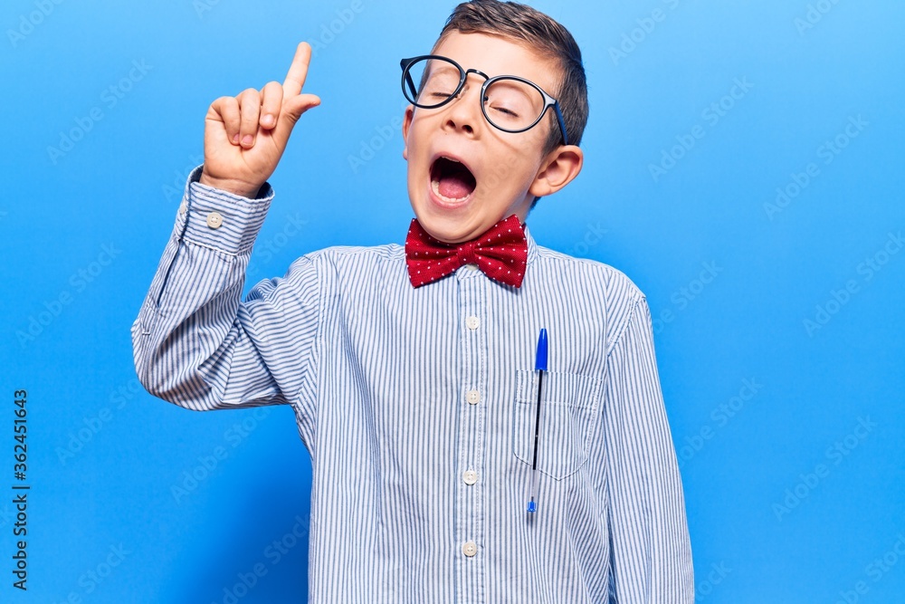 Naklejka premium Cute blond kid wearing nerd bow tie and glasses pointing finger up with successful idea. exited and happy. number one.