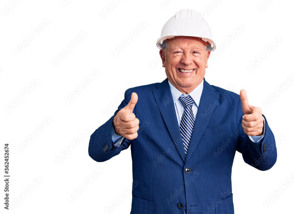 Senior handsome grey-haired man wearing suit and architect hardhat success sign doing positive gesture with hand, thumbs up smiling and happy. cheerful expression and winner gesture.