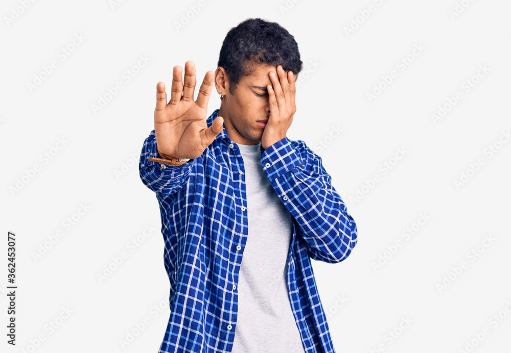 Young african amercian man wearing casual clothes covering eyes with hands and doing stop gesture with sad and fear expression. embarrassed and negative concept. Young african amercian man wearing casual clothes covering eyes with hands and doing stop gesture with sad and fear expression. embarrassed and negative concept.