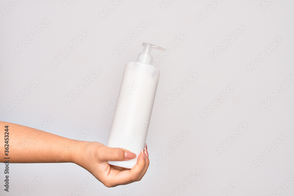 Hand of caucasian young woman holding bottle of body cream over isolated white background Hand of caucasian young woman holding bottle of body cream over isolated white background