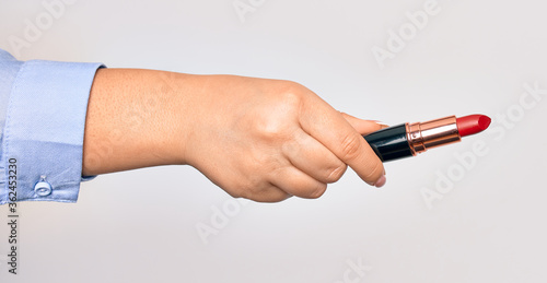 Hand of caucasian young woman holding red lipstick over isolated white background