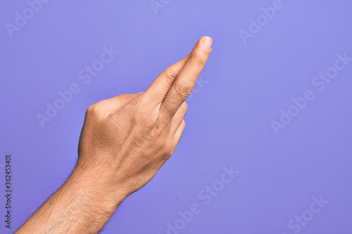 Hand of caucasian young man showing fingers over isolated purple background gesturing fingers crossed, superstition and lucky gesture, lucky and hope expression
