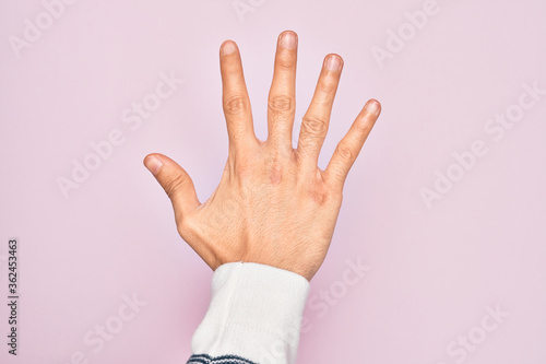 Hand of caucasian young man showing fingers over isolated pink background counting number 5 showing five fingers