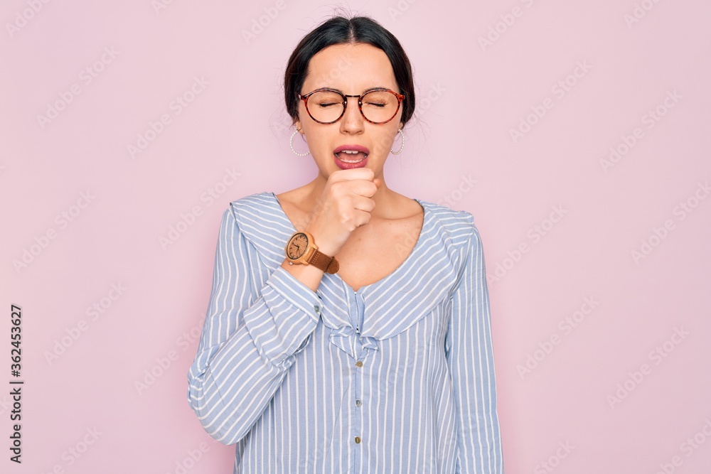 Young beautiful woman wearing casual striped shirt and glasses over pink background feeling unwell and coughing as symptom for cold or bronchitis. Health care concept.