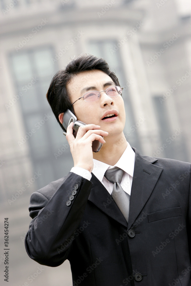 A bespectacled man in business suit talking on the hand phone A bespectacled man in business suit talking on the hand phone