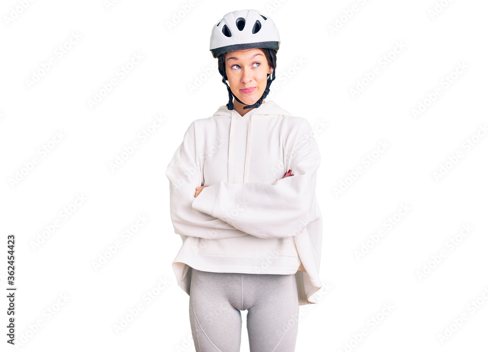 Beautiful brunette young woman wearing bike helmet and sporty clothes smiling looking to the side and staring away thinking. Beautiful brunette young woman wearing bike helmet and sporty clothes smiling looking to the side and staring away thinking.