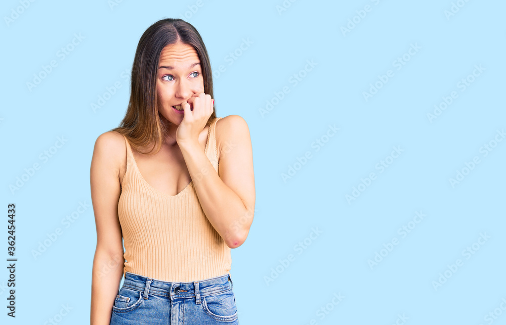 Beautiful brunette young woman wearing casual clothes looking stressed and nervous with hands on mouth biting nails. anxiety problem. Beautiful brunette young woman wearing casual clothes looking stressed and nervous with hands on mouth biting nails. anxiety problem.