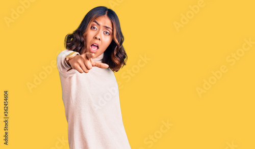Young beautiful mixed race woman wearing winter turtleneck sweater pointing displeased and frustrated to the camera, angry and furious with you