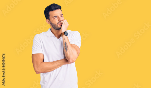Young handsome hispanic man wearing casual clothes looking stressed and nervous with hands on mouth biting nails. anxiety problem. © Krakenimages.com