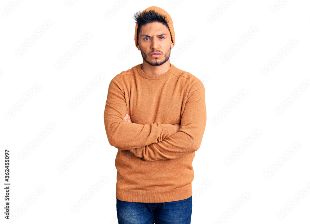 Handsome latin american young man wearing winter sweater and wool hat skeptic and nervous, disapproving expression on face with crossed arms. negative person. Handsome latin american young man wearing winter sweater and wool hat skeptic and nervous, disapproving expression on face with crossed arms. negative person.