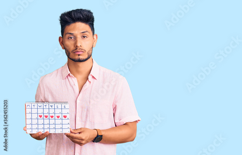 Obraz na plátně Handsome latin american young man holding heart calendar thinking attitude and s
