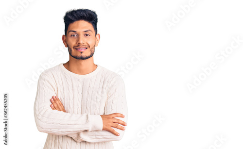 Handsome latin american young man wearing casual winter sweater happy face smiling with crossed arms looking at the camera. positive person.