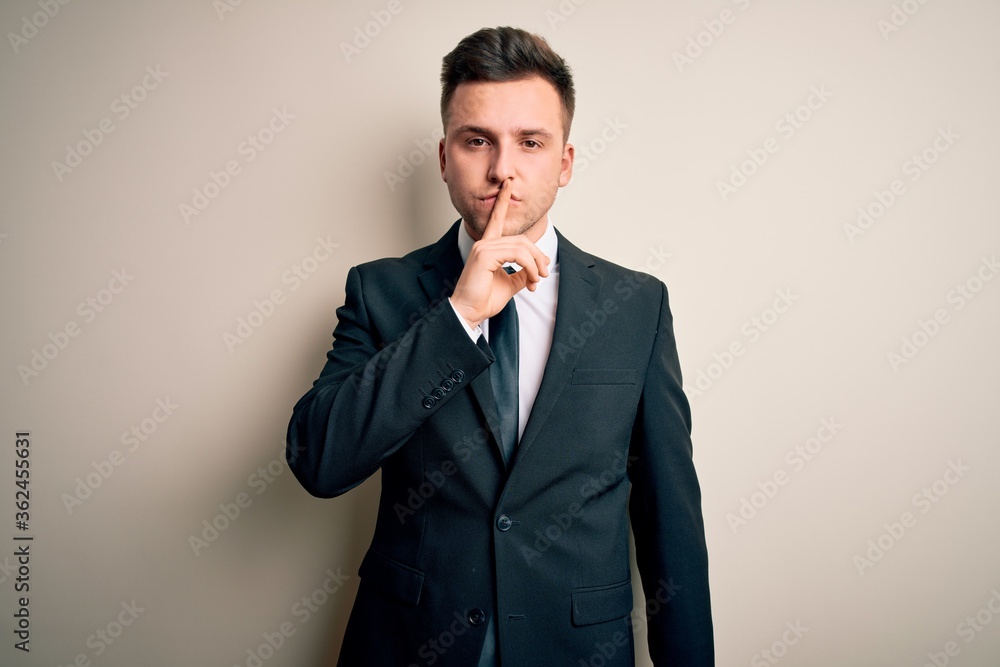 Young handsome business man wearing elegant suit and tie over isolated background asking to be quiet with finger on lips. Silence and secret concept. Young handsome business man wearing elegant suit and tie over isolated background asking to be quiet with finger on lips. Silence and secret concept.
