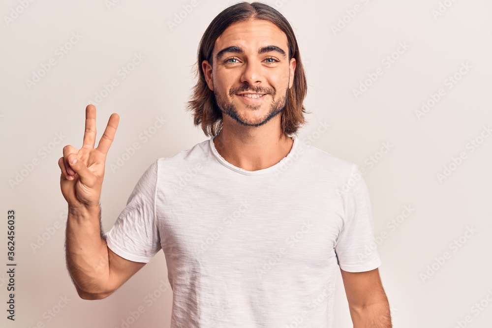 Young handsome man wearing casual clothes smiling with happy face winking at the camera doing victory sign. number two. Young handsome man wearing casual clothes smiling with happy face winking at the camera doing victory sign. number two.