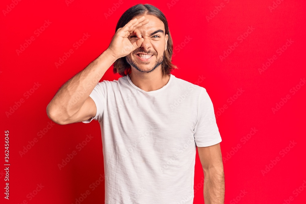 Fototapeta premium Young handsome man wearing casual clothes doing ok gesture with hand smiling, eye looking through fingers with happy face.
