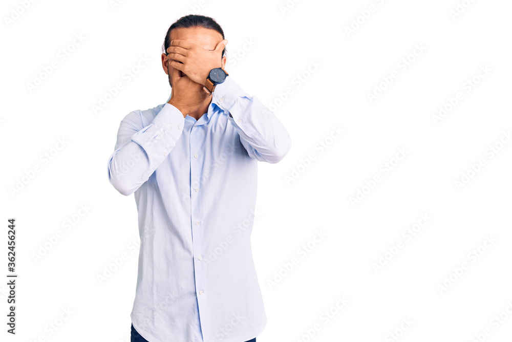 Young handsome man wearing business clothes covering eyes and mouth with hands, surprised and shocked. hiding emotion Young handsome man wearing business clothes covering eyes and mouth with hands, surprised and shocked. hiding emotion