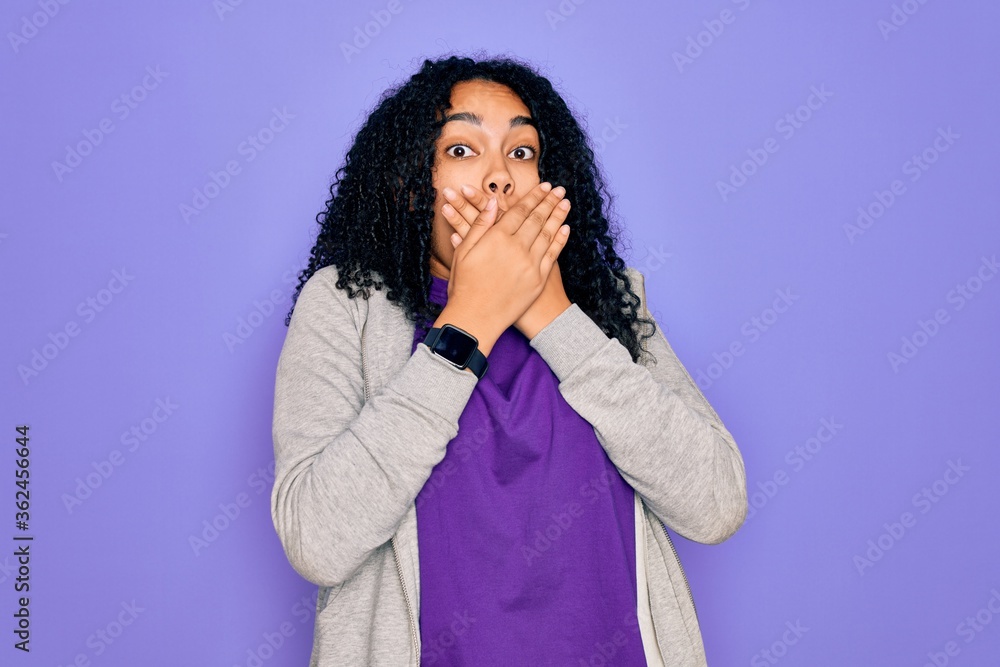 Young african american sporty woman wearing casual sweatshirt over purple background shocked covering mouth with hands for mistake. Secret concept.