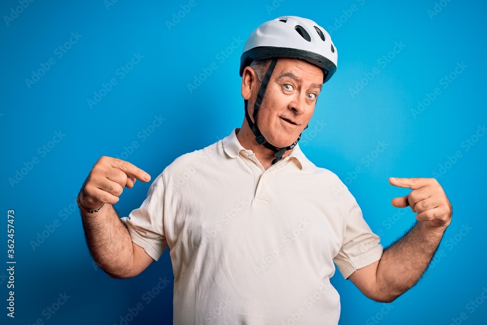 Middle age hoary cyclist man wearing bike security helmet over isolated blue background looking confident with smile on face, pointing oneself with fingers proud and happy. Middle age hoary cyclist man wearing bike security helmet over isolated blue background looking confident with smile on face, pointing oneself with fingers proud and happy.